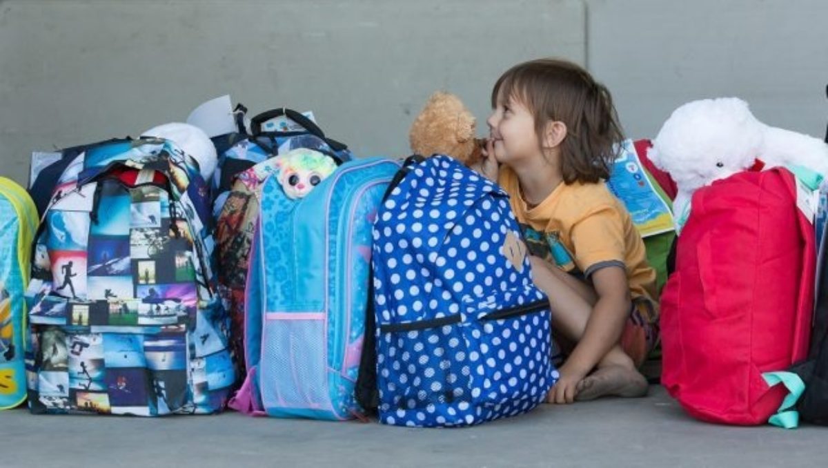 Backpacks4sakids young boy sitting among donated backpacks